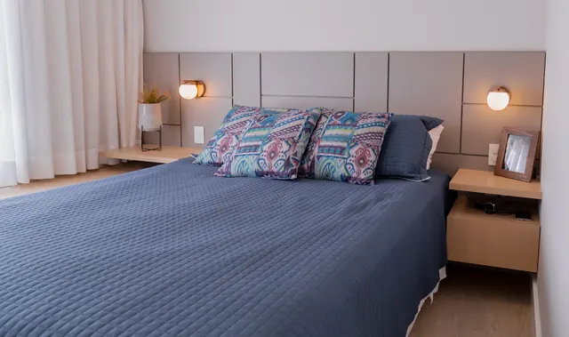 Quarto com cabeceira estofada e criados-mudos em madeira clara