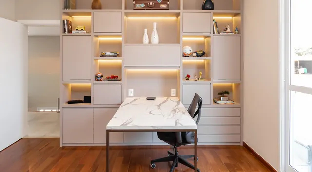 Escritório com estante iluminada e mesa de tampo marmorizado